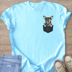 Chihuahua in pocket wearing American flag bandana and sunglasses on light blue t-shirt.