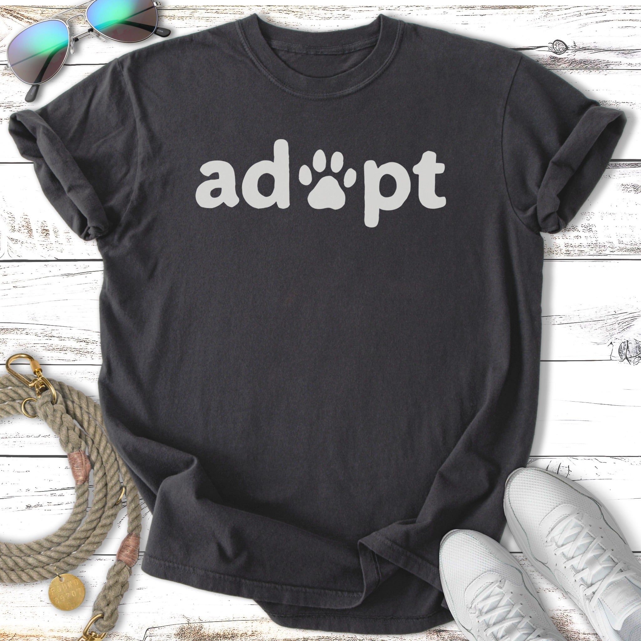 Dark t-shirt with white "adopt" text and paw print graphic.