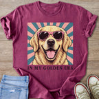 Golden retriever wearing pink sunglasses on a sunburst background, text reads "IN MY GOLDEN ERA."