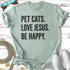 T-shirt with "Pet Cats. Love Jesus. Be Happy." text.