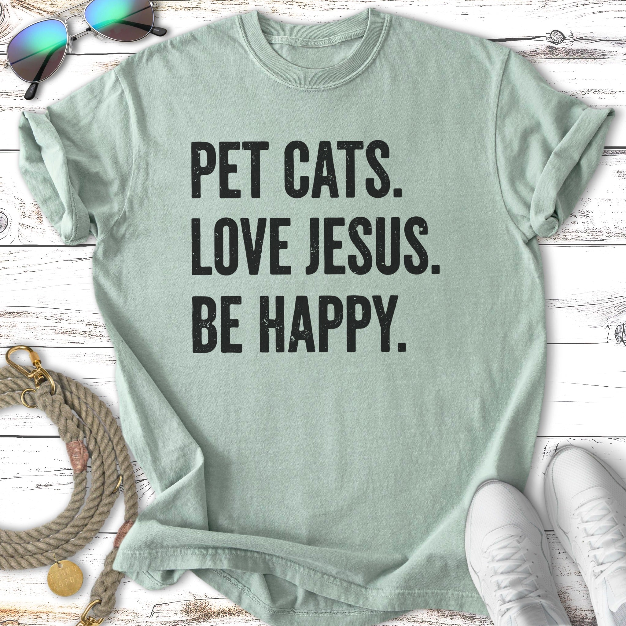 T-shirt with "Pet Cats. Love Jesus. Be Happy." text.