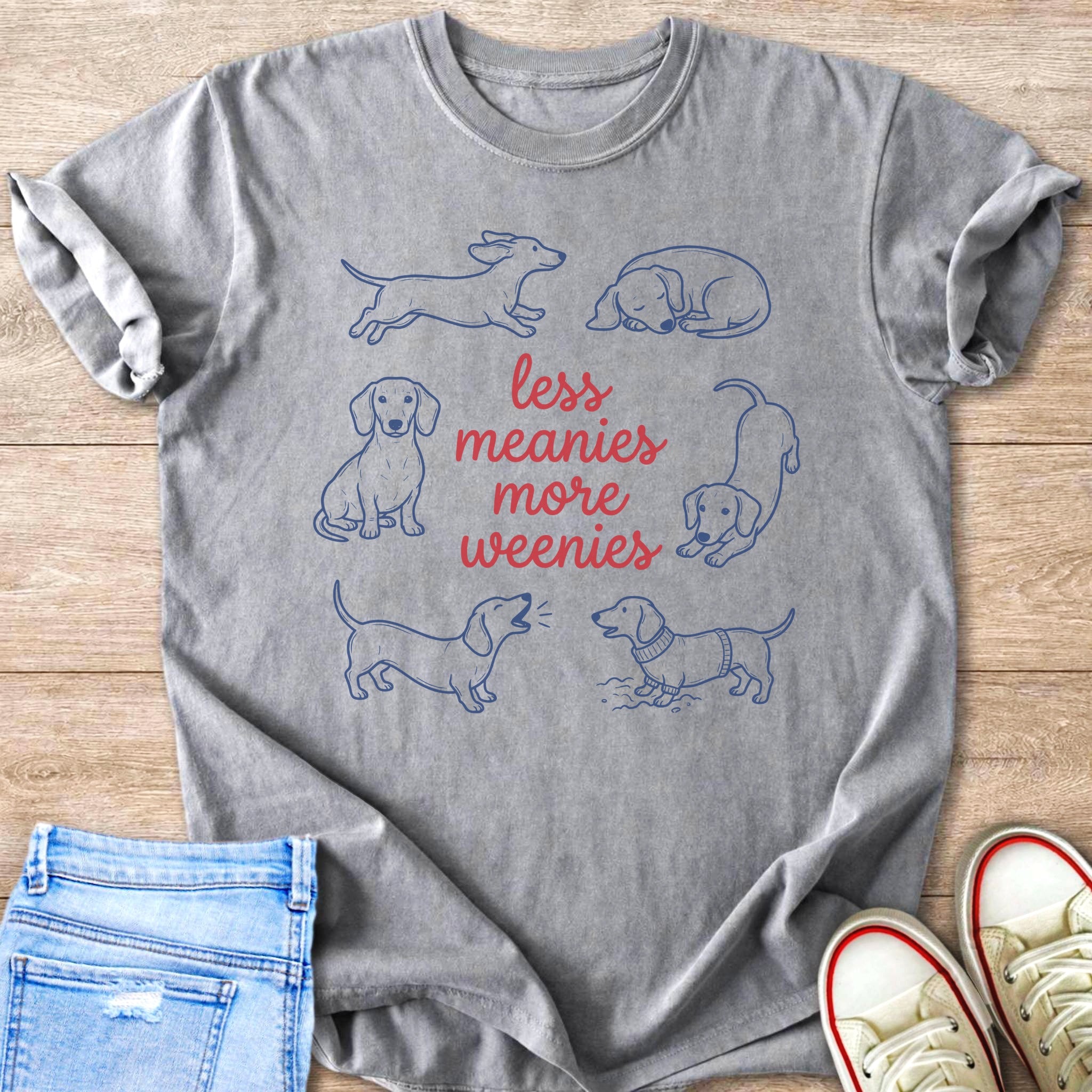 Grey t-shirt with blue line drawings of dachshunds and red text reading "less meanies more weenies."