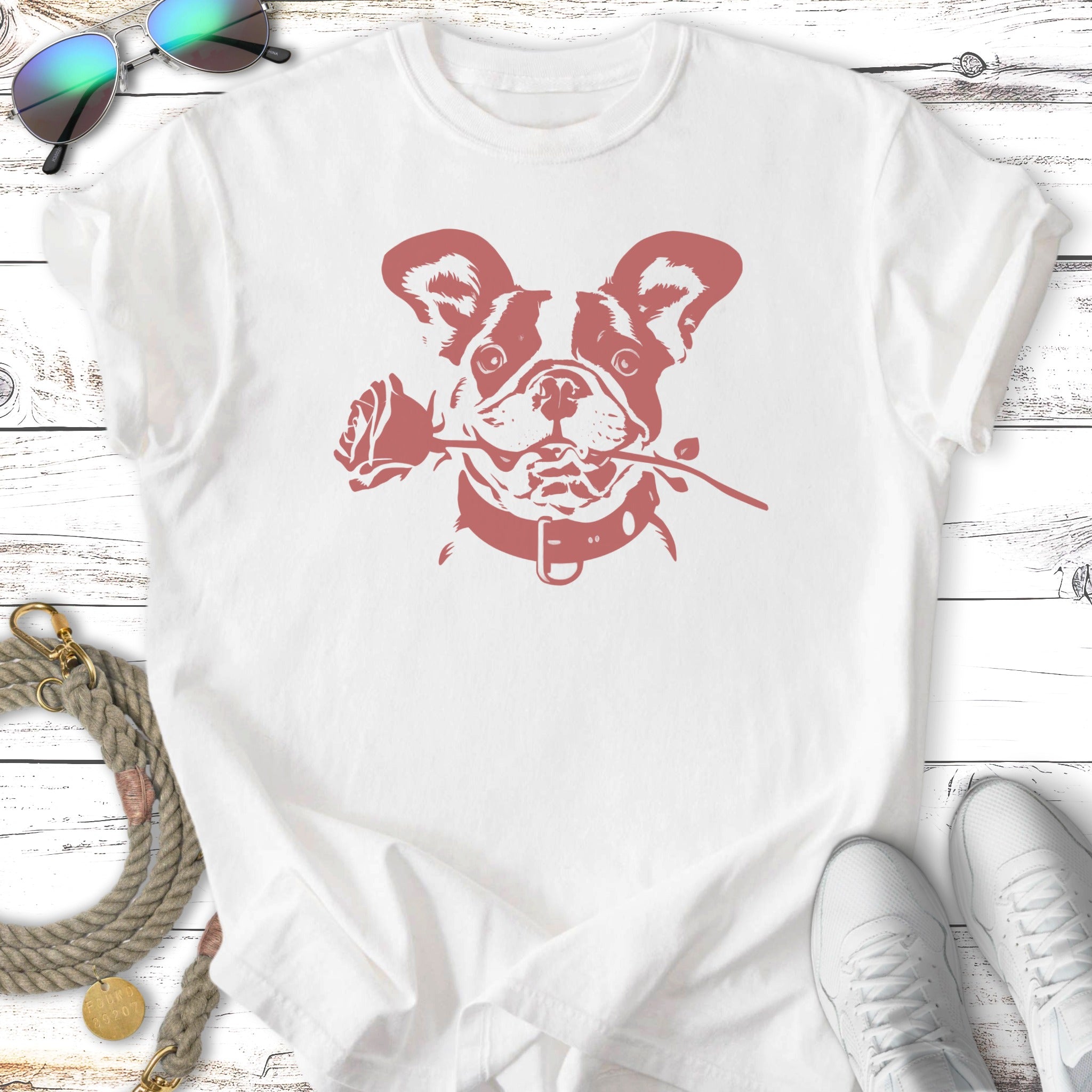 French bulldog holding a rose in its mouth, printed on a white t-shirt.