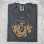 German Shepherd in cowboy hat with cows, wearing a graphic t-shirt.