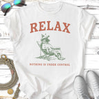 White t-shirt with "RELAX NOTHING IS UNDER CONTROL" and dog on lounge chair graphic.