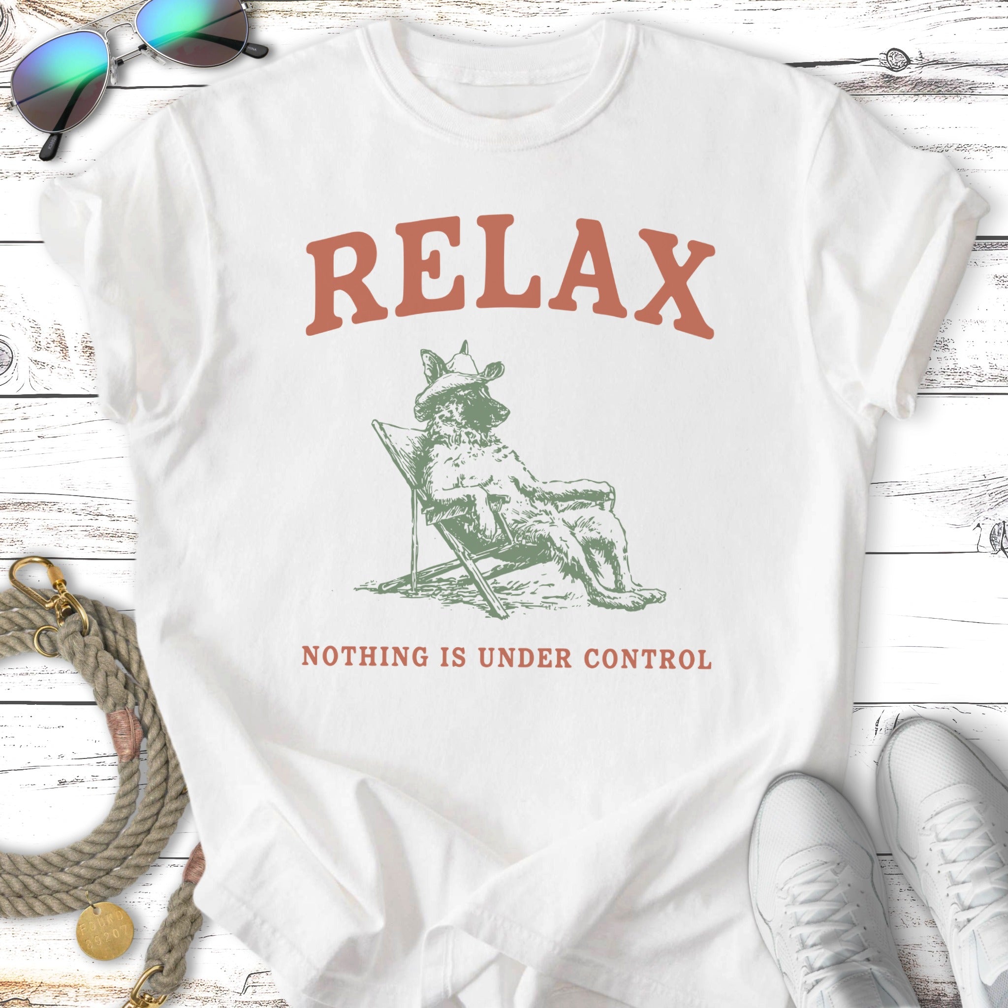 White t-shirt with "RELAX NOTHING IS UNDER CONTROL" and dog on lounge chair graphic.