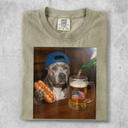 Dog wearing a blue baseball cap holding a hot dog, with a beer and American flag.