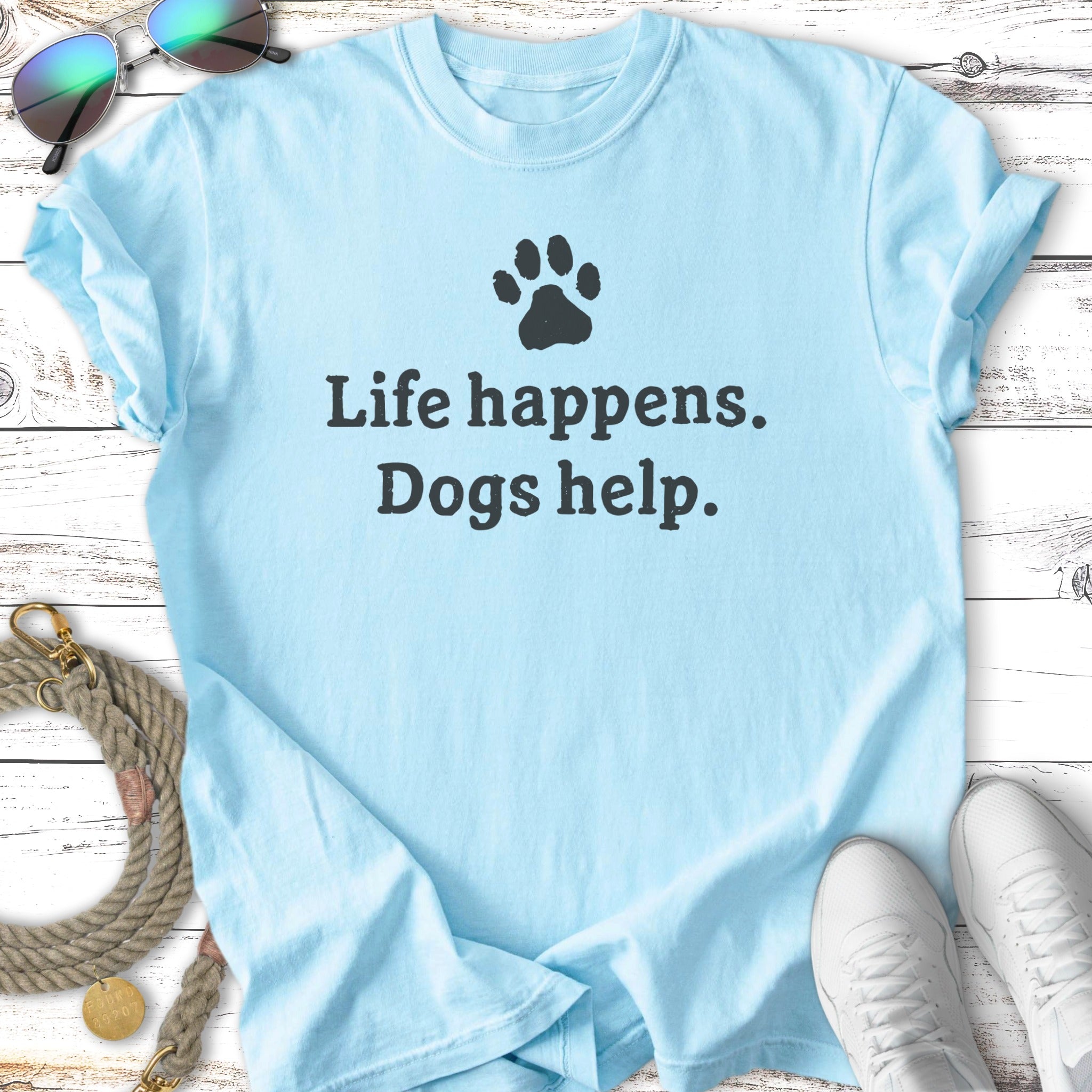 Light blue t-shirt with "Life happens. Dogs help." text and paw print.