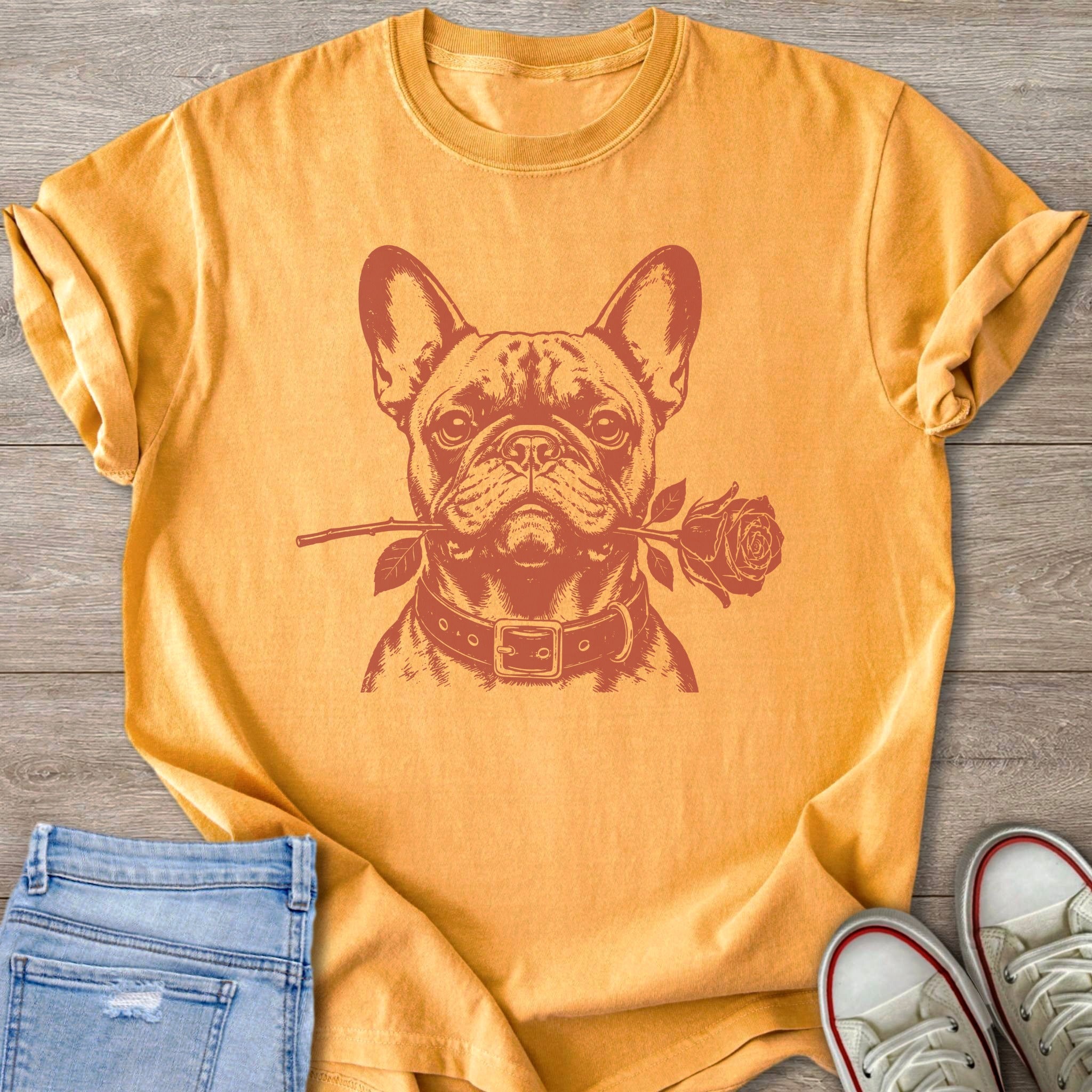 French bulldog with a rose in its mouth on an orange t-shirt.