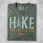 Green t-shirt with "Hike and Pet All the Dogs" text and pine tree graphic.
