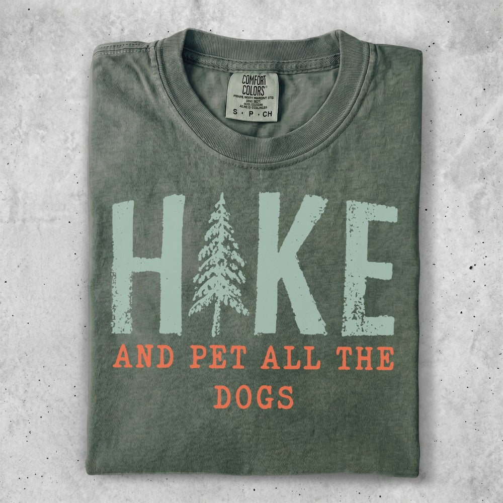 Green t-shirt with "Hike and Pet All the Dogs" text and pine tree graphic.