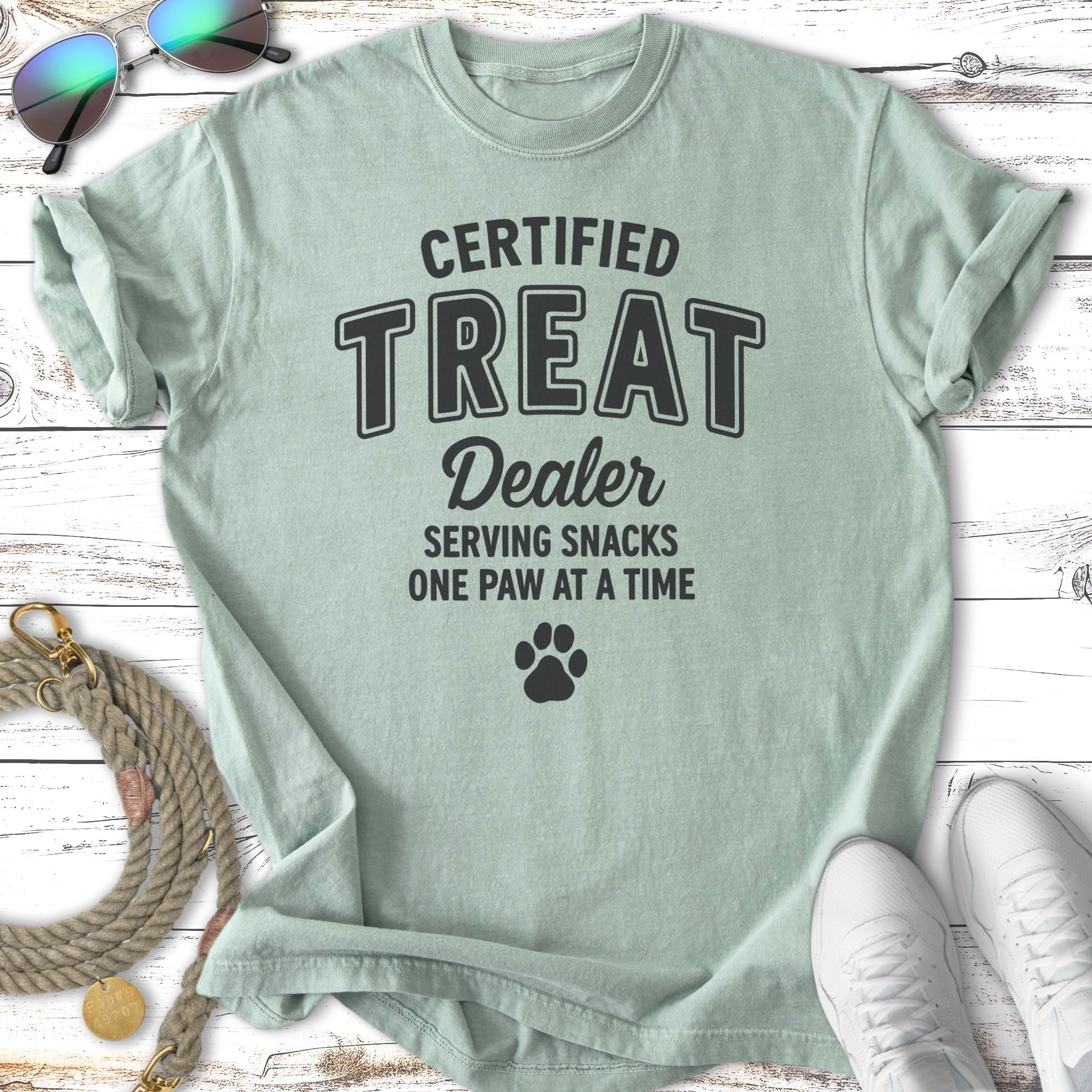 Light green t-shirt reading "Certified Treat Dealer Serving Snacks One Paw at a Time".