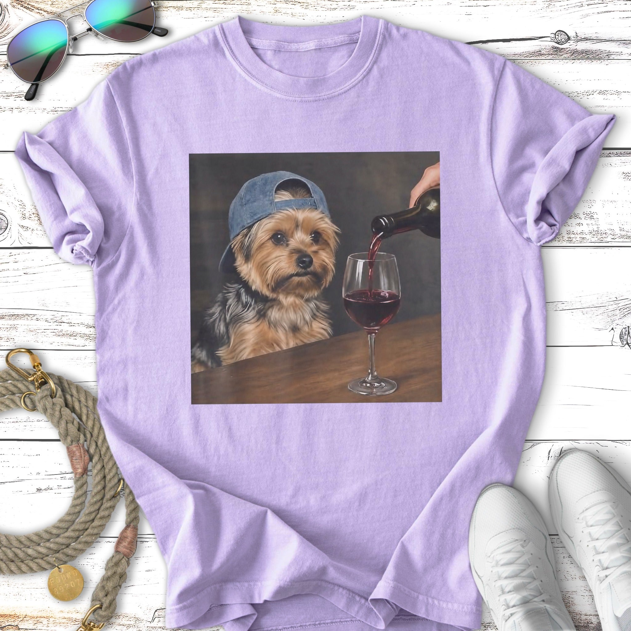 Yorkshire terrier wearing a baseball cap pours red wine into a glass.