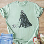 Darth Vader walks an AT-ST walker on a leash on a light green t-shirt.