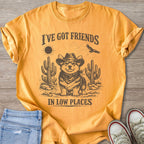 Yellow t-shirt with cowboy corgi, cacti, sun, eagle, and text "I'VE GOT FRIENDS IN LOW PLACES".
