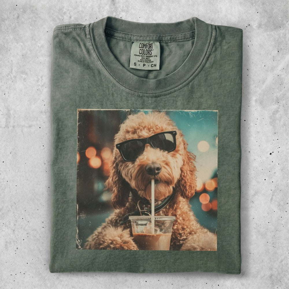 Fluffy dog wearing sunglasses drinks from a cup with a straw.