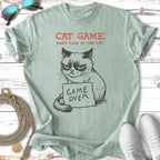 Green t-shirt with grumpy cat drawing, text "CAT GAME DON'T LOOK AT THE CAT. GAME OVER".