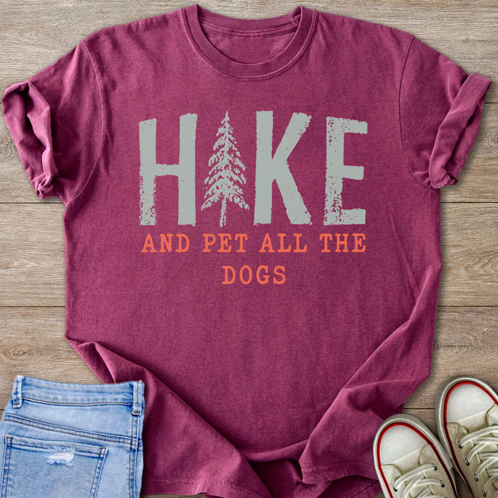 Magenta t-shirt with "HIKE AND PET ALL THE DOGS" text and a pine tree graphic.