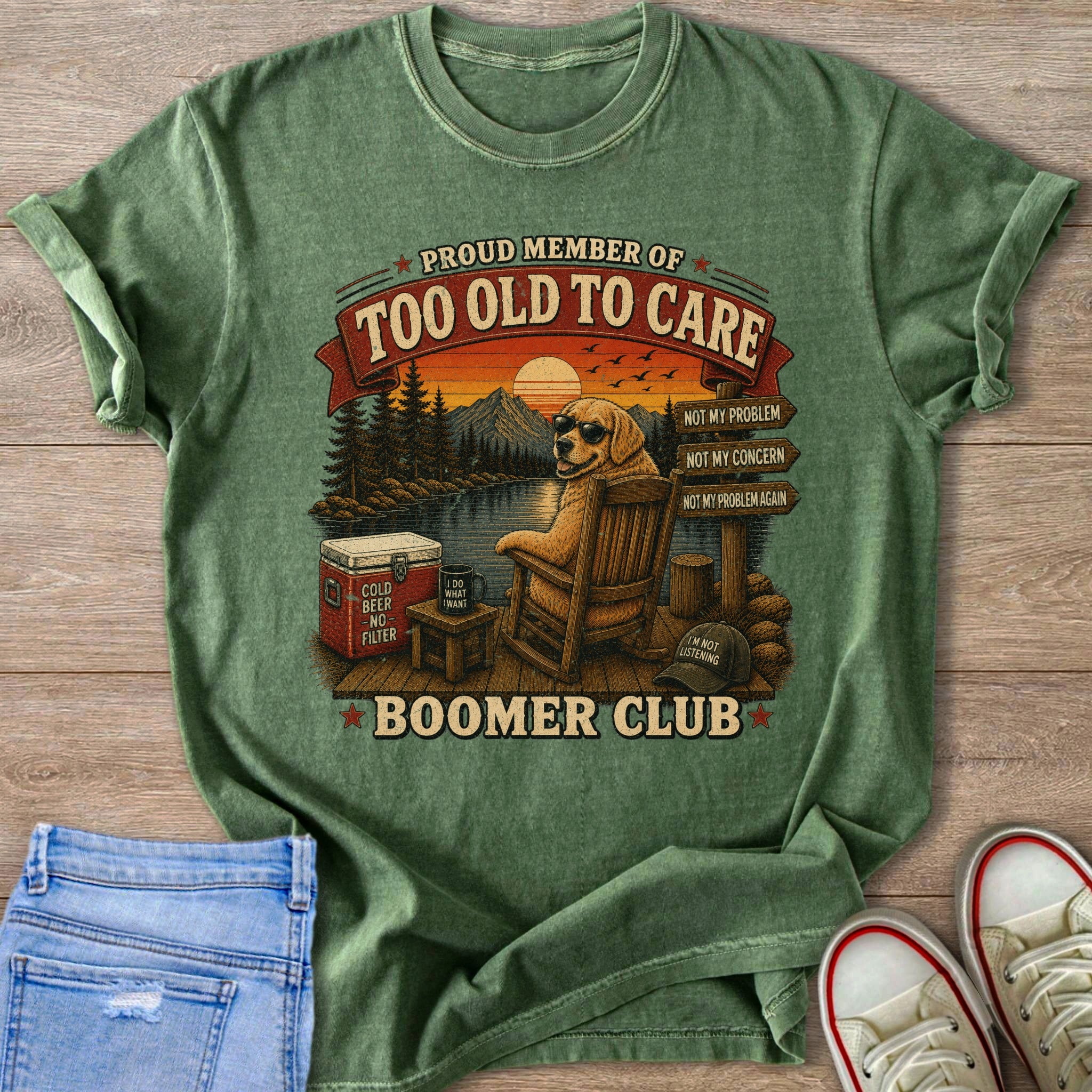 Green t-shirt with a graphic of a dog in a rocking chair by a lake, text "Too Old To Care Boomer Club".