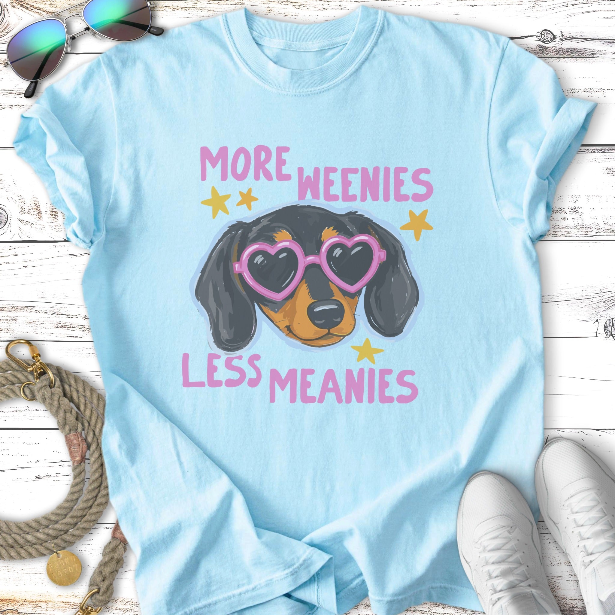 Light blue t-shirt with dachshund wearing heart-shaped sunglasses, text reads "More Weenies, Less Meanies".