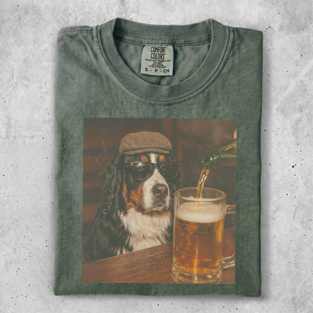 Bernese Mountain Dog wearing sunglasses and cap, looking at beer.