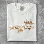 White t-shirt with cowboys and corgis riding horses illustration.