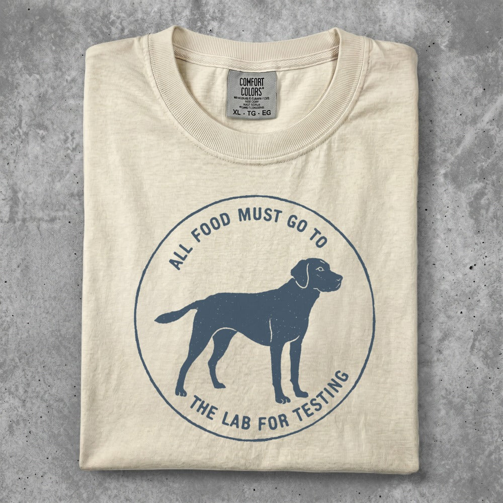 Cream t-shirt with blue graphic of a dog and text "all food must go to the lab for testing".