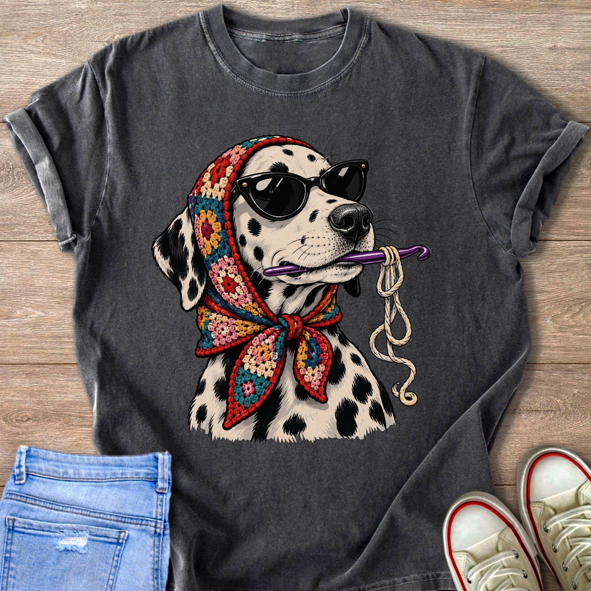 Dalmatian dog wearing sunglasses and a colorful crochet scarf, holding a crochet hook and yarn.