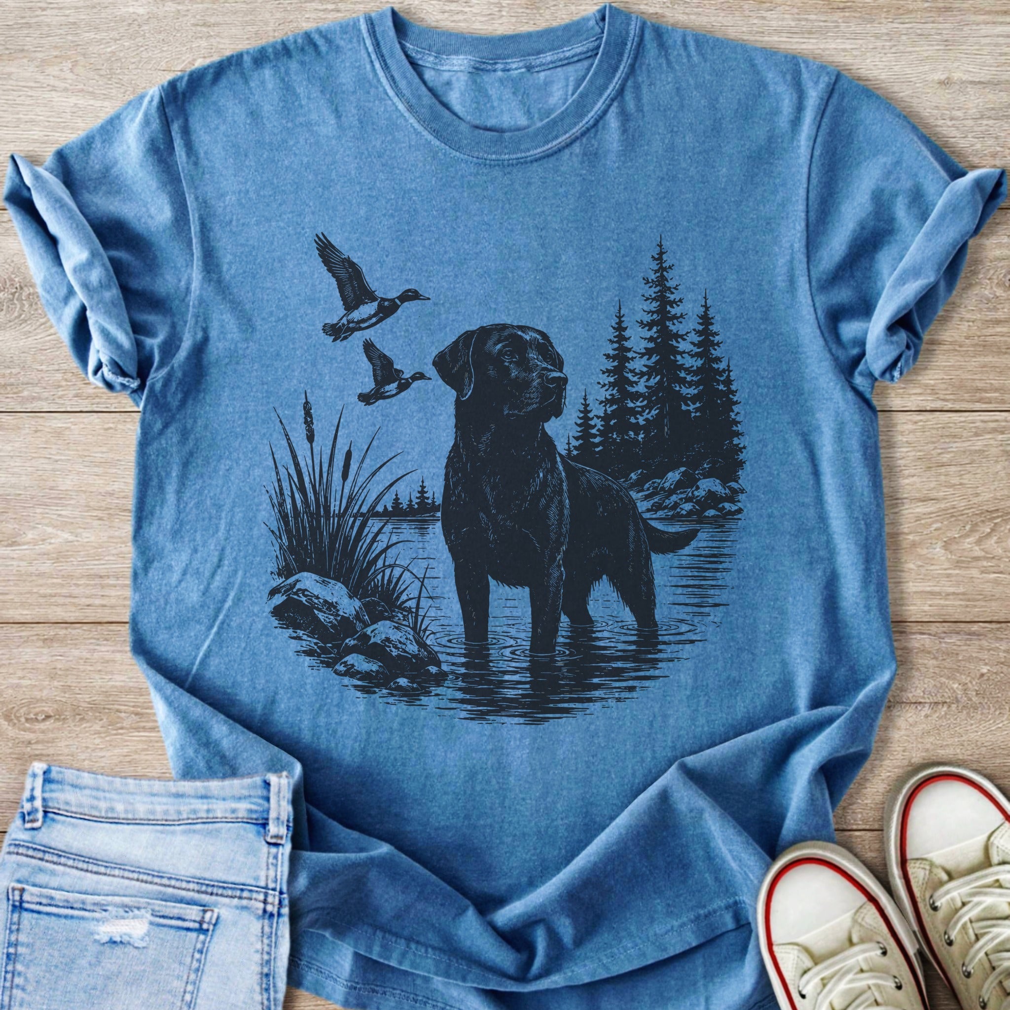 Black lab stands in water with ducks flying past and trees in background.
