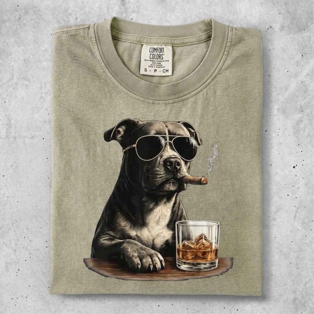 Pit bull wearing sunglasses and smoking a cigar next to a glass of whiskey.