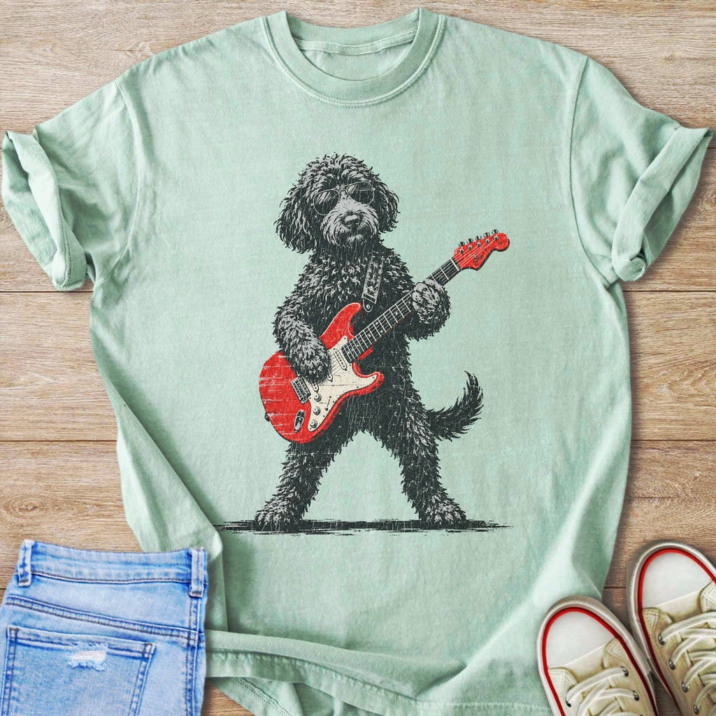 Black dog wearing sunglasses plays a red electric guitar on a light green shirt.
