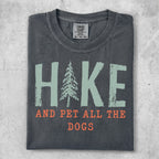 Dark grey t-shirt with "HIKE AND PET ALL THE DOGS" text and a pine tree graphic.