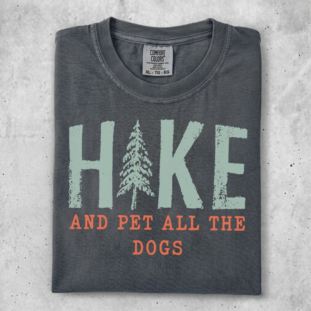 Dark grey t-shirt with "HIKE AND PET ALL THE DOGS" text and a pine tree graphic.