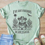 Light green t-shirt with a graphic of a corgi wearing a cowboy hat and bandana in a desert landscape.