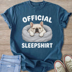Blue t-shirt with a beige bulldog napping in a bed, text reads "OFFICIAL SLEEPSHIRT".