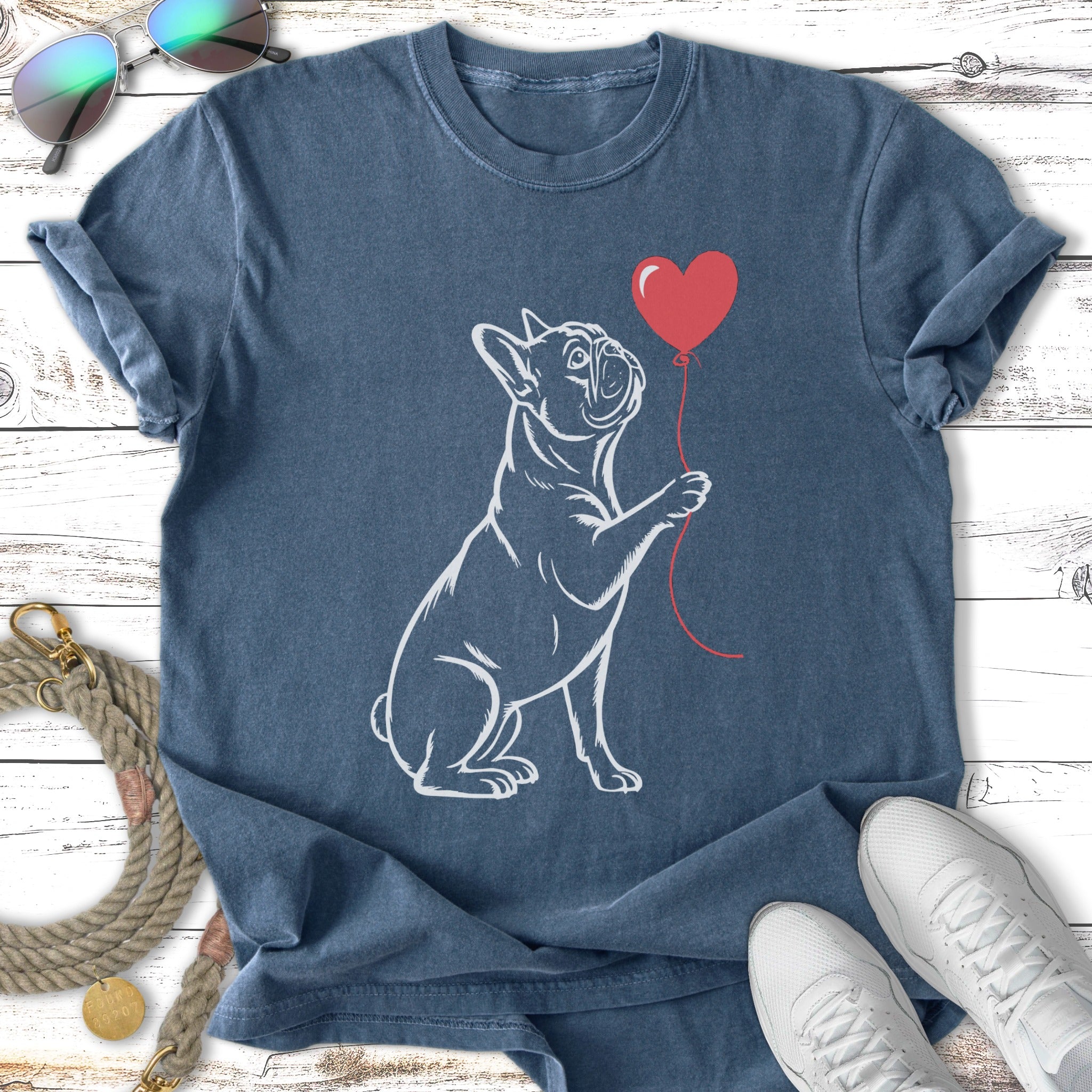 French bulldog holding a red heart balloon on a blue t-shirt.