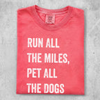 Coral t-shirt with white text reading "RUN ALL THE MILES, PET ALL THE DOGS".