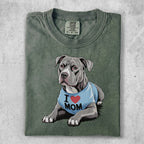 Pitbull wearing a blue "I Love Mom" shirt, lying down.