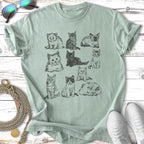 Nine sketched kittens in various playful poses on a light green t-shirt.