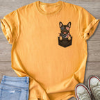 French bulldog wearing sunglasses and bandana peeking from a pocket on a yellow t-shirt.