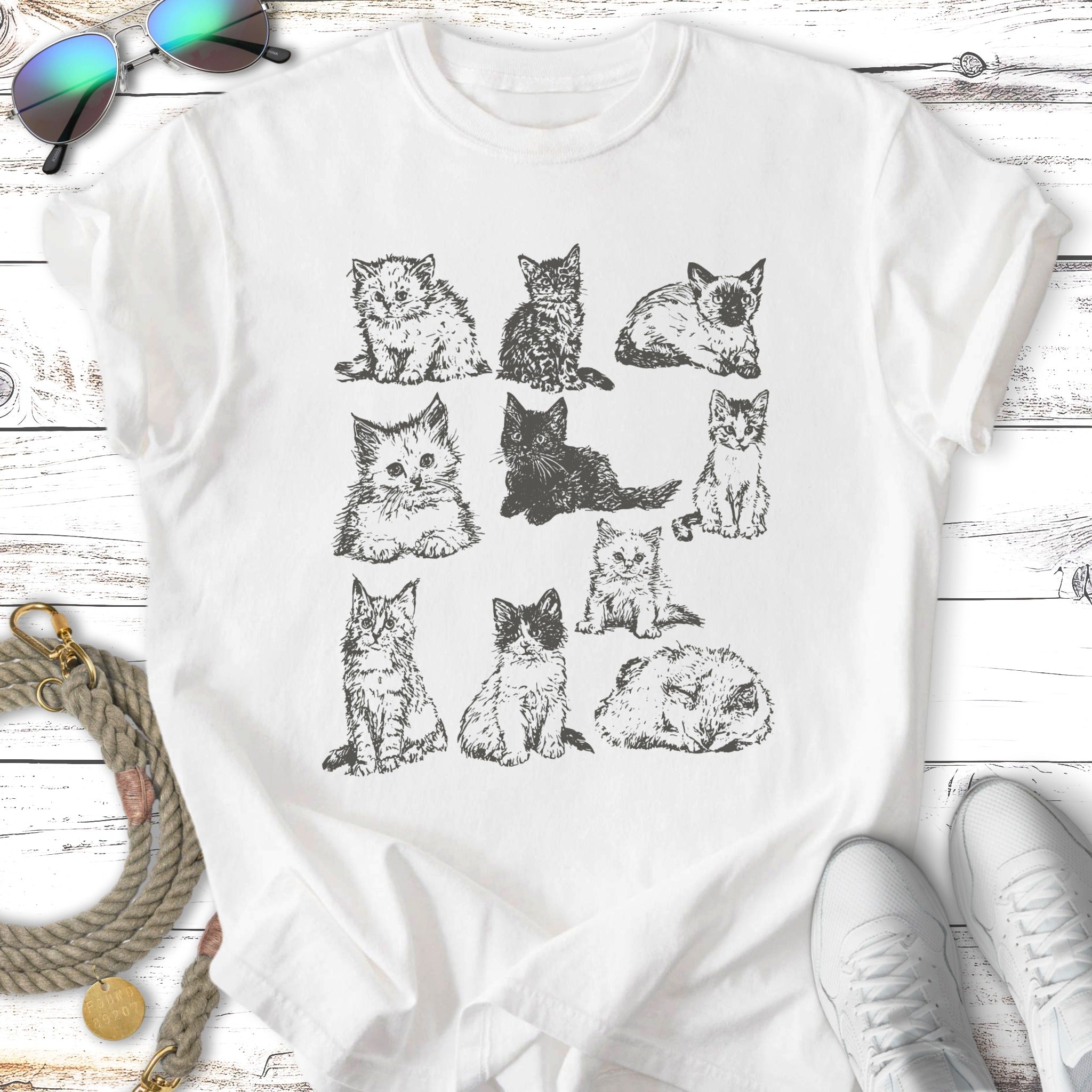 Line drawing of nine kittens in various playful poses on a white t-shirt.