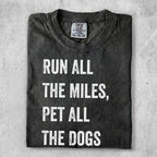 Dark t-shirt with white text "Run all the miles, pet all the dogs."