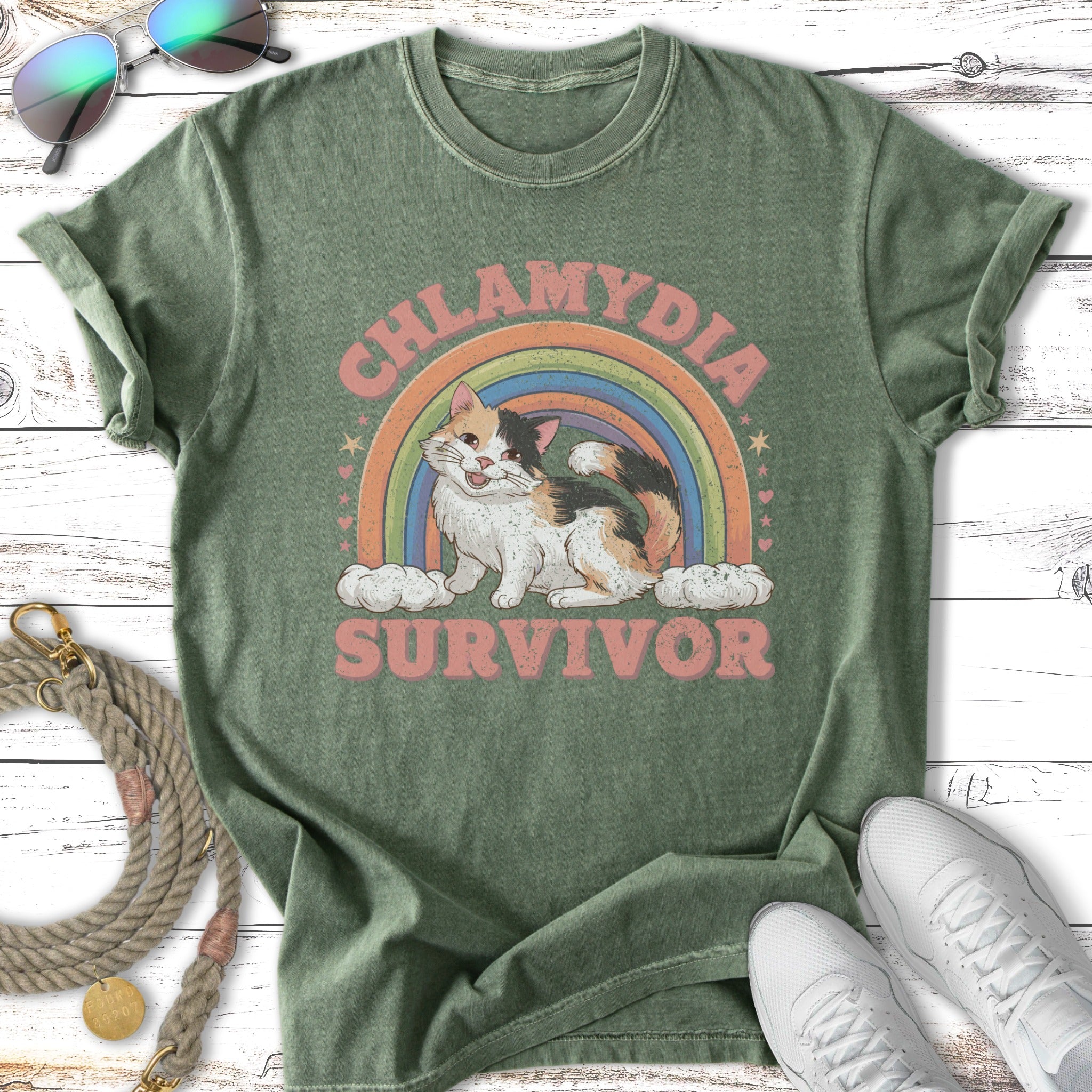 "Chlamydia Survivor" text with a cat on a rainbow and clouds, t-shirt design.