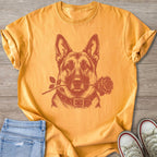 German Shepherd wearing a collar holds a rose in its mouth on a yellow shirt.