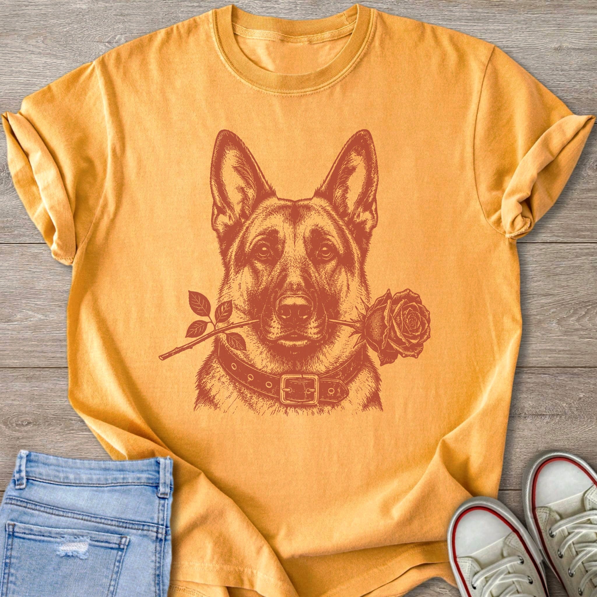 German Shepherd wearing a collar holds a rose in its mouth on a yellow shirt.