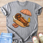 Dachshund wearing heart sunglasses relaxes in a hot dog bun with umbrella and sunscreen.