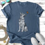 German Shepherd looking at butterfly on dark blue t-shirt.
