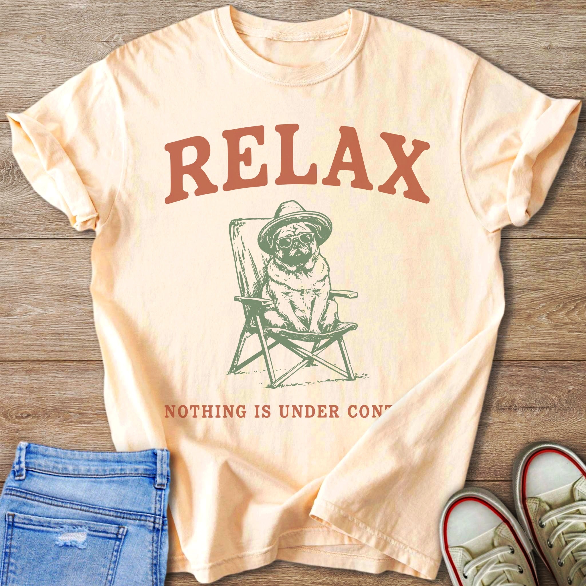 Peach t-shirt with "RELAX" and a pug wearing a hat and sunglasses sitting in a chair.