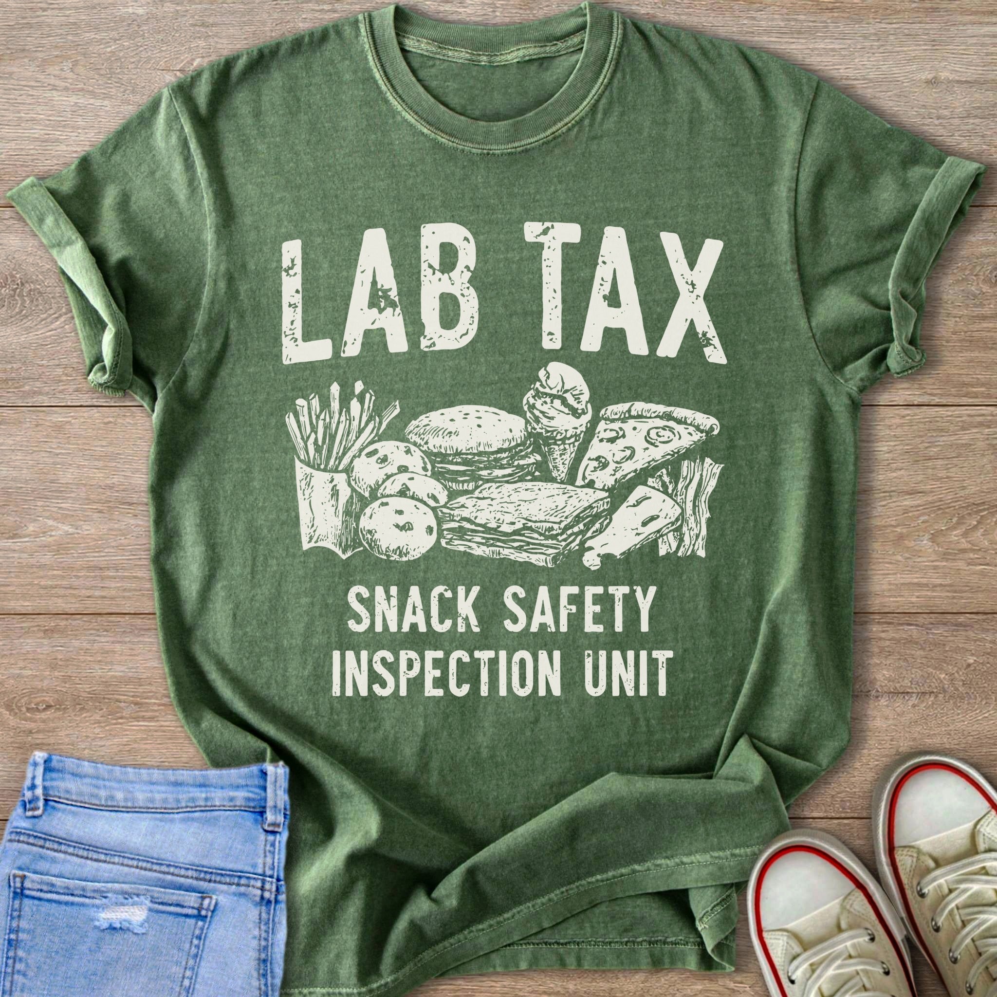 Green t-shirt with white text "LAB TAX SNACK SAFETY INSPECTION UNIT" above junk food illustration.