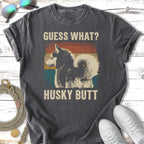 Graphic t-shirt with vintage sunset and husky dog, text reads "GUESS WHAT? HUSKY BUTT".